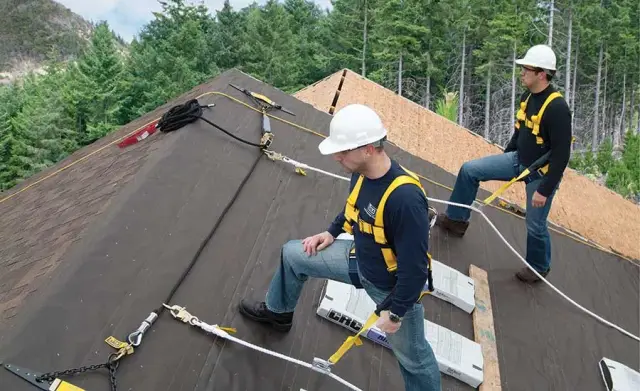Roofing Companies Huntsville crew working tied off with fall protection harnesses on a steep roof